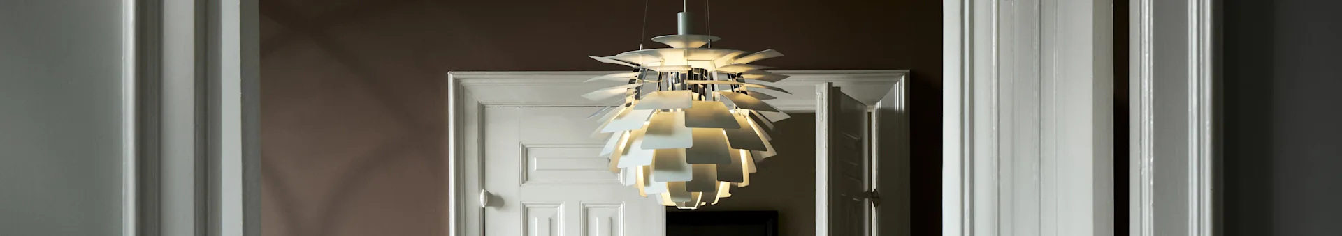 Um candeeiro de teto branco e escultural com múltiplas camadas ilumina uma entrada.