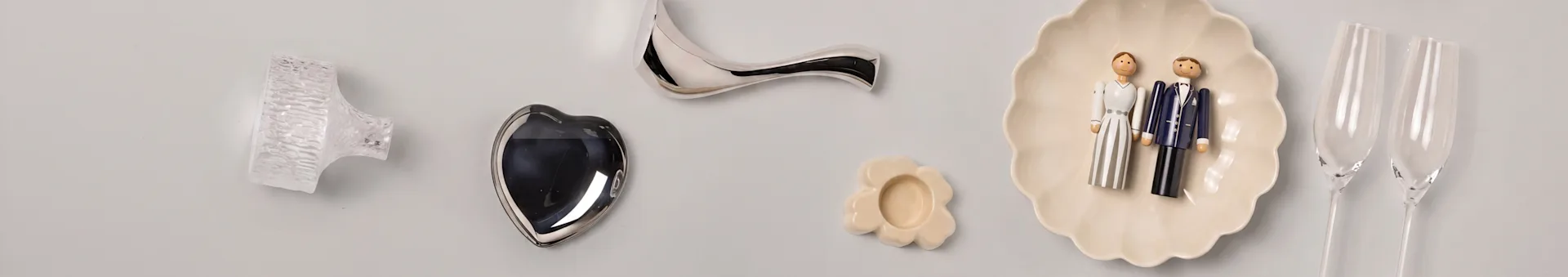 Artigos decorativos: puxador de vidro, coração prateado, pega curva, prato de flor, figuras de noivos, flutes de champanhe.